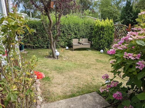 Blick von der Terrasse in den Garten und gemütlicher Gartenbank, um die Natur zu genießen